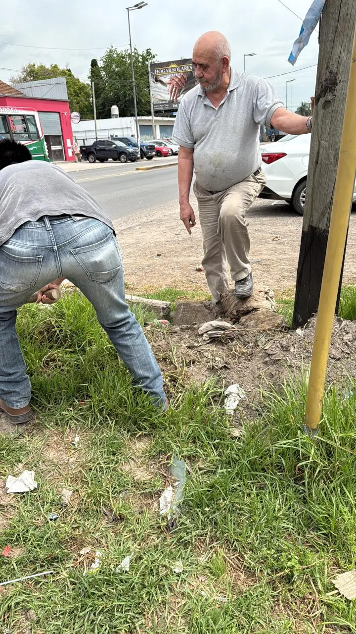 El abuelo de la familia Ledesma, de pie junto a un poste recién plantado en la vereda, mientras otro operario termina de asentarlo