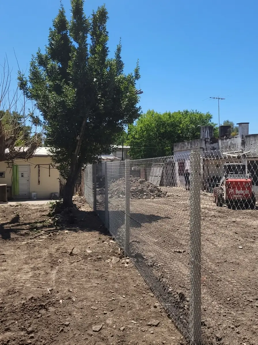 Alambrado romboidal dividiendo un terreno, con los postes plantados en línea